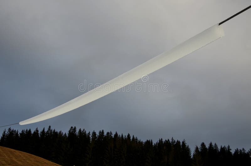 Power lines frozen by a large layer of ice in the shape of a cylinder with icicles. icing loads the columns, which are overloaded and fall and break on the ground. artificial snow on the ski lift.