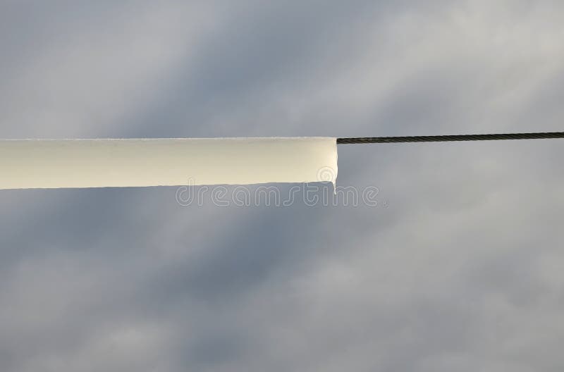 Power lines frozen by a large layer of ice in the shape of a cylinder with icicles. icing loads the columns, which are overloaded stock image