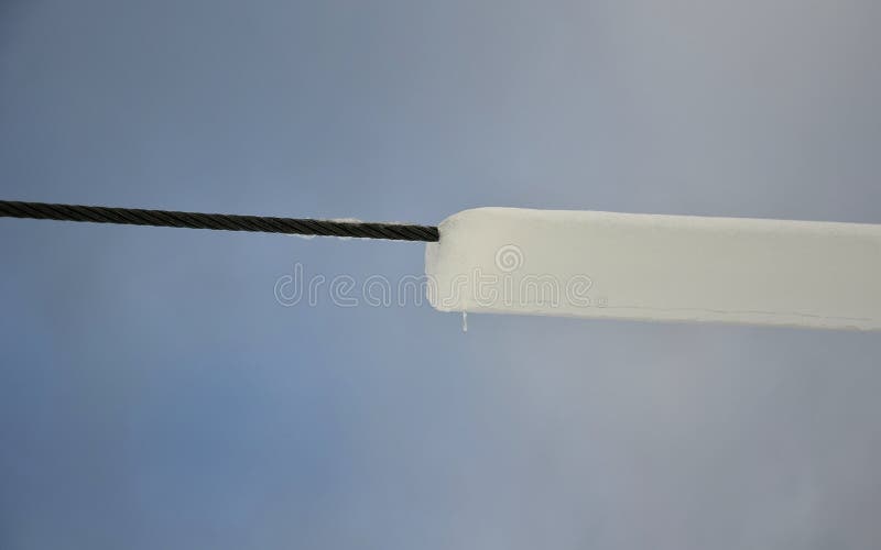 Power lines frozen by a large layer of ice in the shape of a cylinder with icicles. icing loads the columns, which are overloaded stock photos