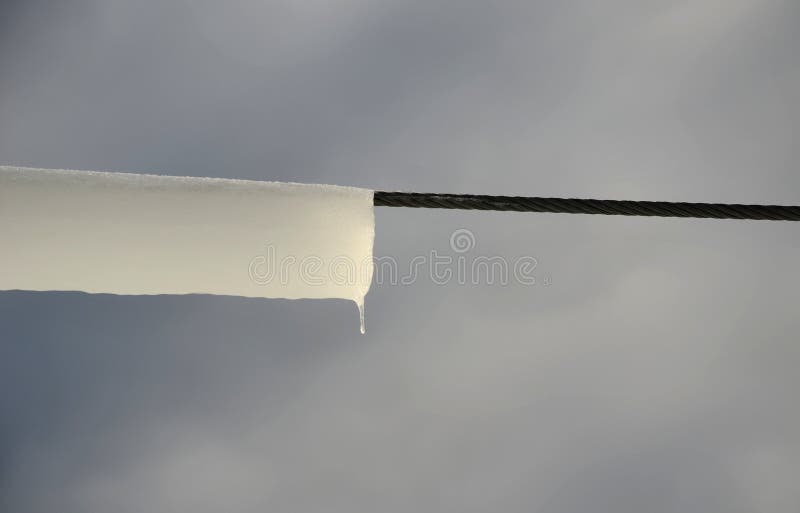 Power lines frozen by a large layer of ice in the shape of a cylinder with icicles. icing loads the columns, which are overloaded stock photos