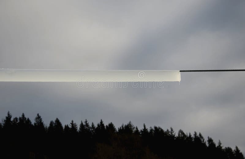 Power lines frozen by a large layer of ice in the shape of a cylinder with icicles. icing loads the columns, which are overloaded stock photography