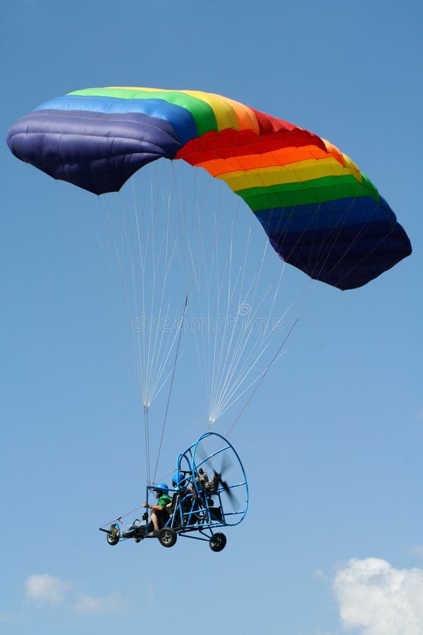 Pilot má svobodu powered padáku s rainbow-barevné padák.