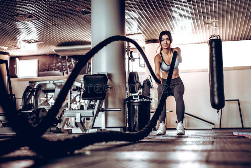 Powerful attractive muscular woman trainer do battle workout with ropes at the gym royalty free stock photography Powerful attractive muscular woman trainer do battle workout with ropes at the gym royalty free stock photography