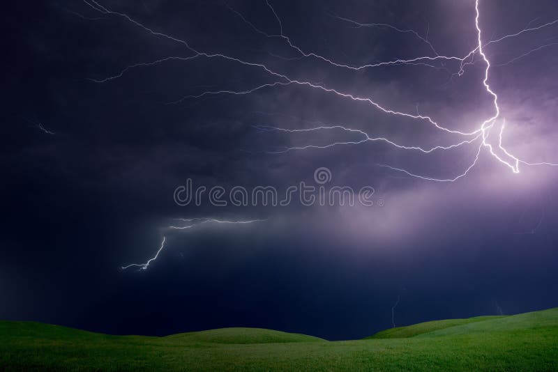 Powerful lightnings in dark stormy sky above green grass hills royalty free stock photography Powerful lightnings in dark stormy sky above green grass hills royalty free stock photography