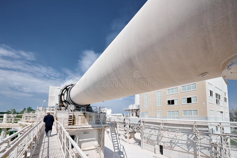 Powerful rotating kiln for calx roasting at production plant. Contemporary manufacturing industrial complex and problems of environment protection