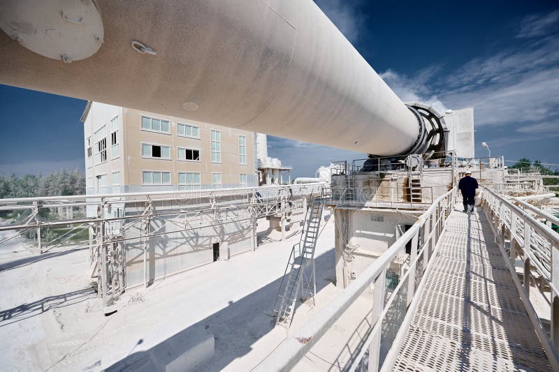 Powerful rotating kiln for calx roasting at production plant. Contemporary manufacturing industrial complex and problems of environment protection