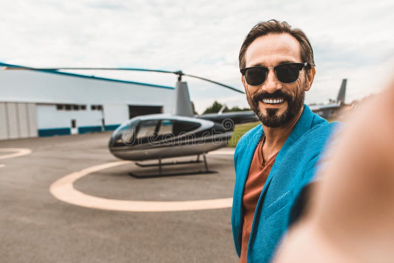 Pozytywny mężczyzna bierze selfies z ono uśmiecha się i helikopterem obraz stock Pozytywny mężczyzna bierze selfies z ono uśmiecha się i helikopterem obraz stock