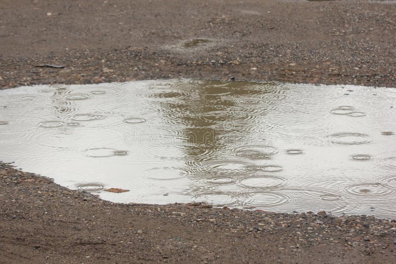 Pozze dell'acqua con le gocce di pioggia ed i cerchi dell'acqua immagini stock Pozze dell'acqua con le gocce di pioggia ed i cerchi dell'acqua immagini stock