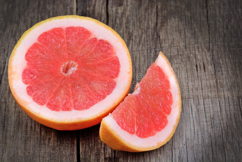 Połówka i kawałek czerwony grapefruitowy na drewno stole zdjęcia stock Połówka i kawałek czerwony grapefruitowy na drewno stole zdjęcia stock