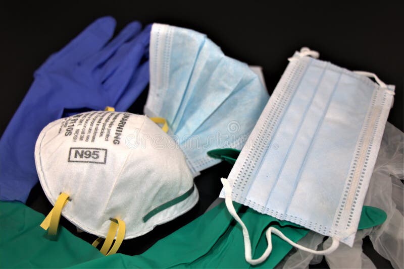PPE or Personal Protective Equipment against black background. N95 Respirator, surgical procedure mask and pairs of different medical examination gloves. Top view, Abstract photo. PPE or Personal Protective Equipment against black background. N95 Respirator, surgical procedure mask and pairs of different medical examination gloves. Top view, Abstract photo