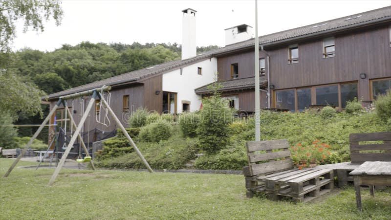 Prachtig gebouwde yard dichtbij het moderne blokhuis in regenachtig weer actie Binnenplaats met met de hand gemaakte banken en stock fotografie Prachtig gebouwde yard dichtbij het moderne blokhuis in regenachtig weer actie Binnenplaats met met de hand gemaakte banken en stock fotografie