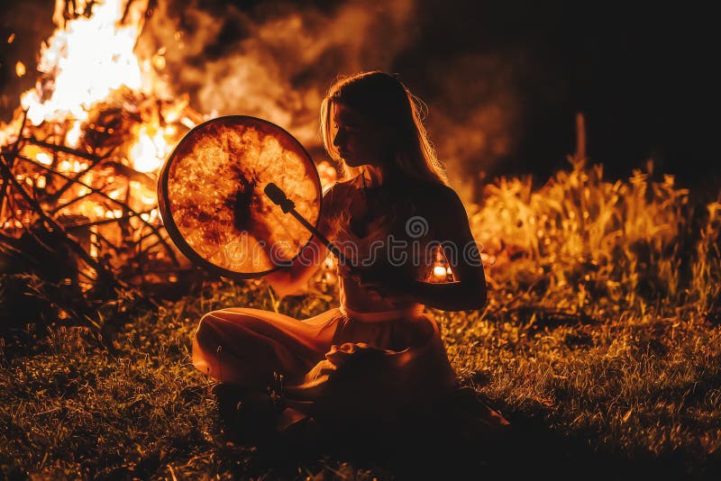 Prachtig shamandig meisje dat in de natuur op shaman frame drum speelt.