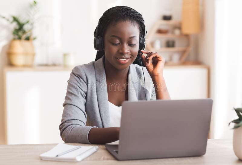Prachtige vrouwelijke callcenter-operator met hoofdtelefoon en typering op laptop