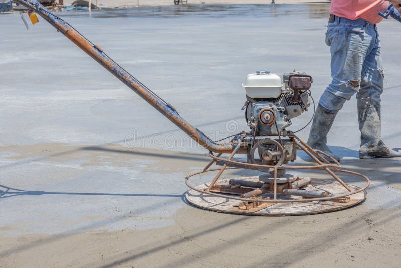 Pracownicy używają betonowe polerownicze maszyny dla cementu po tym jak Nalewający mieszającego beton obrazy stock Pracownicy używają betonowe polerownicze maszyny dla cementu po tym jak Nalewający mieszającego beton obrazy stock