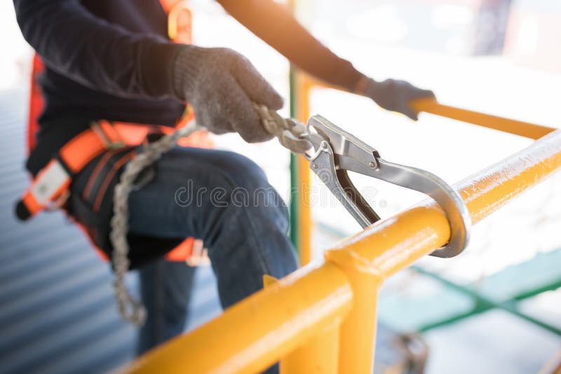 Pracownik budowlany noszący uprzęż bezpieczeństwa i linię bezpieczeństwa pracujący na wysokim stanowisku