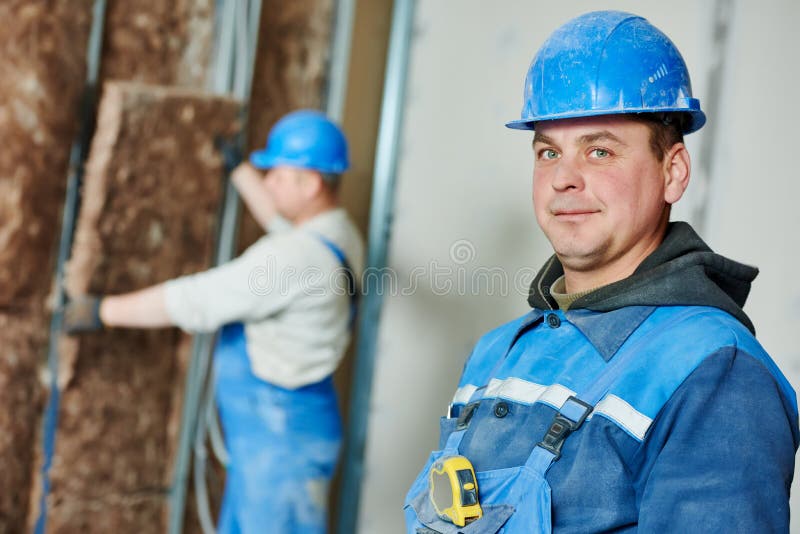 Cheerful plasterer worker at a indoors wall insulation works. Cheerful plasterer worker at a indoors wall insulation works