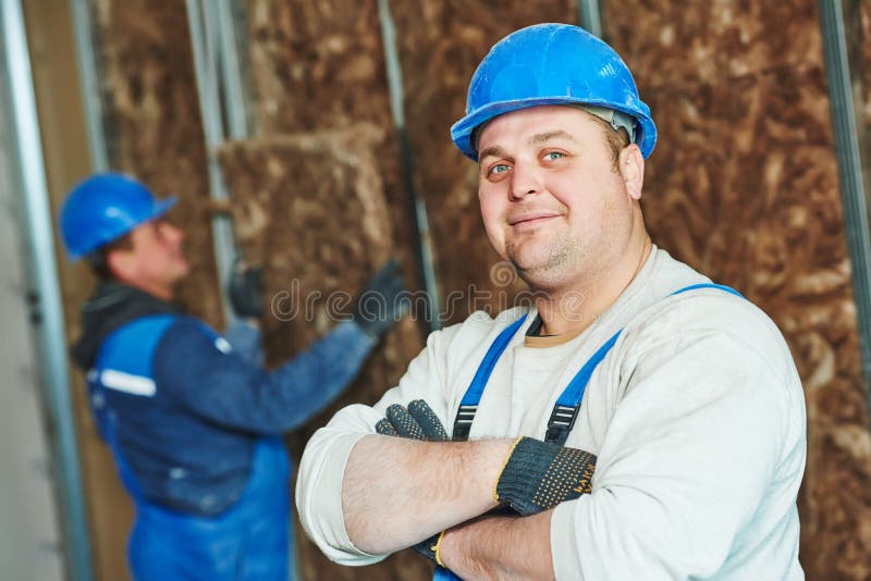 Cheerful plasterer worker at a indoors wall insulation works. Cheerful plasterer worker at a indoors wall insulation works