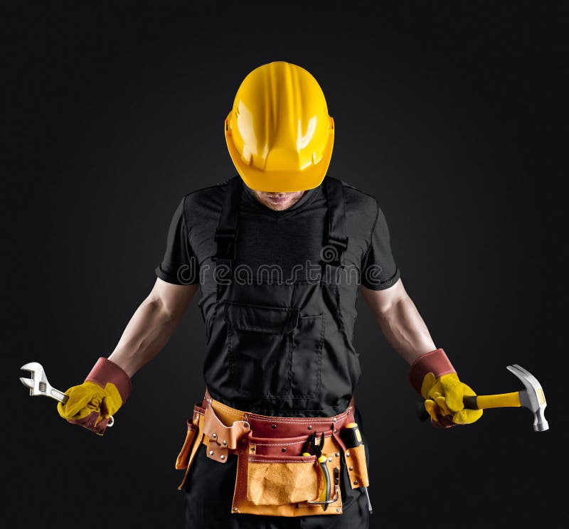 Construction worker in helmet with hammer and wrench on dark background. Construction worker in helmet with hammer and wrench on dark background