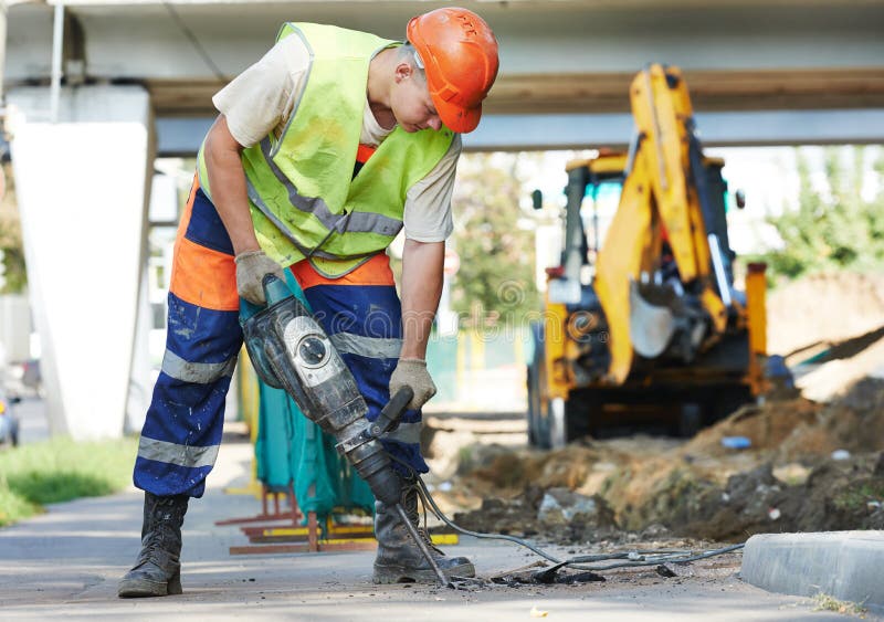 Builder worker with pneumatic hammer drill equipment breaking asphalt at road construction site. Builder worker with pneumatic hammer drill equipment breaking asphalt at road construction site