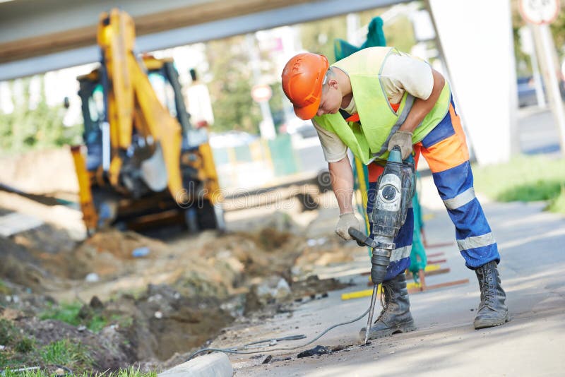 Builder worker with pneumatic hammer drill equipment breaking asphalt at road construction site. Builder worker with pneumatic hammer drill equipment breaking asphalt at road construction site