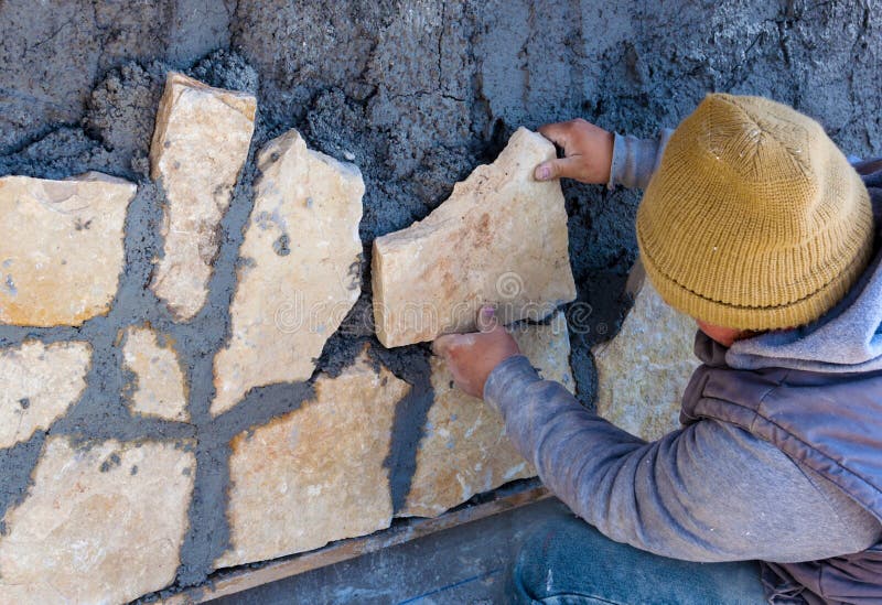 Pracownik wtykający kamienny powlekanie na fasadzie