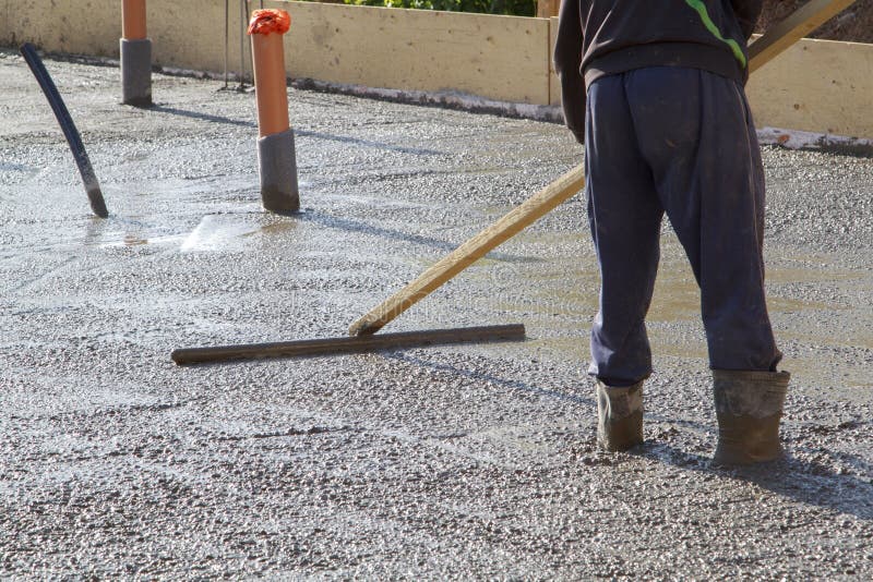 pracownik zr?wnuje ?wie?? betonow? p?yt? z specjalnym drewnianym workin zdjęcia stock pracownik zr?wnuje ?wie?? betonow? p?yt? z specjalnym drewnianym workin zdjęcia stock