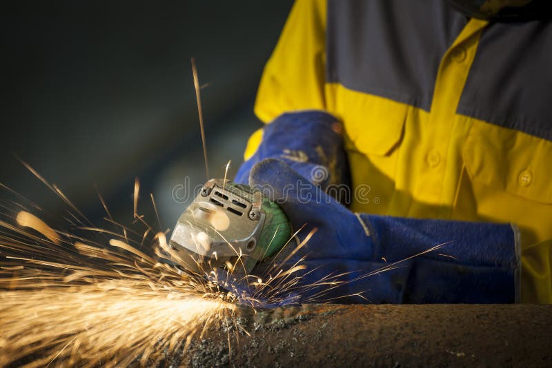 Pracownika szlifierski metal w zakładzie produkcyjnym, iskier latać obrazy stock Pracownika szlifierski metal w zakładzie produkcyjnym, iskier latać obrazy stock