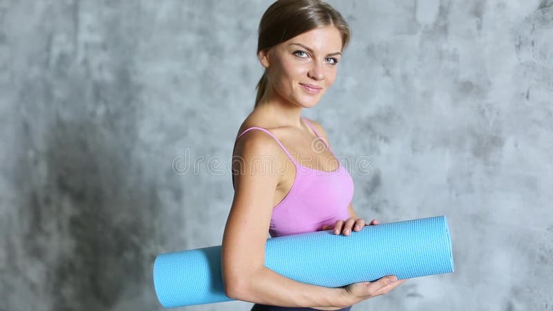 Young beautiful girl with yoga mat smiling.