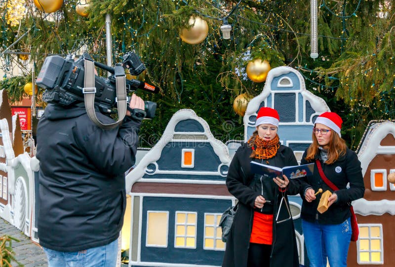 Prague, Czech Republic - December 24, 2015: Girls near decorated Christmas tree on the Old Town Square, singing Christmas carols. At Christmas, a large number of tourists come to Prague. Prague, Czech Republic - December 24, 2015: Girls near decorated Christmas tree on the Old Town Square, singing Christmas carols. At Christmas, a large number of tourists come to Prague.