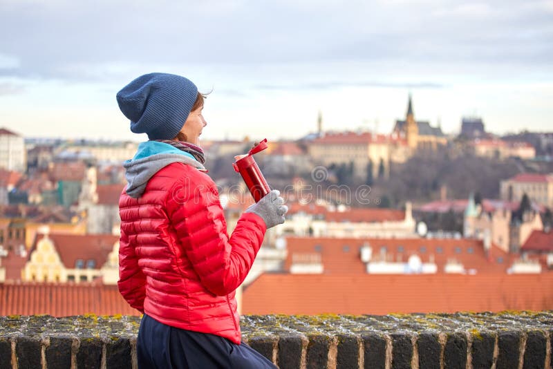 praga Una muchacha goza de una vista panorámica de la ciudad vieja y bebe una bebida caliente de un termo imagen de archivo libre de regalías praga Una muchacha goza de una vista panorámica de la ciudad vieja y bebe una bebida caliente de un termo imagen de archivo libre de regalías