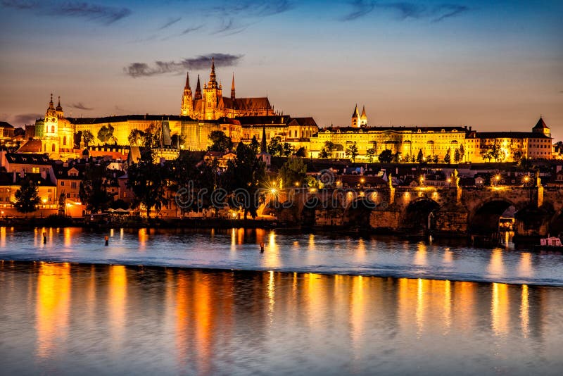 Praga castillo sobre el atardecer, reflexión sobre el un rio.