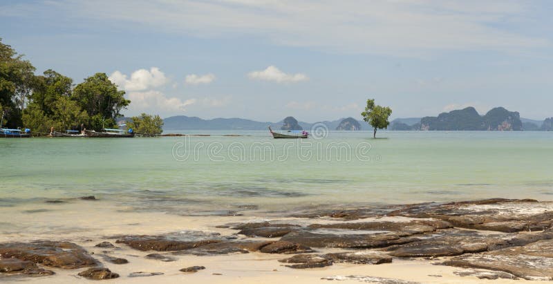 Praia bonita com opiniões do mar e um barco de pesca tailandês tradicional Praia bonita com árvores tropicais com uma onda do mar imagens de stock Praia bonita com opiniões do mar e um barco de pesca tailandês tradicional Praia bonita com árvores tropicais com uma onda do mar imagens de stock