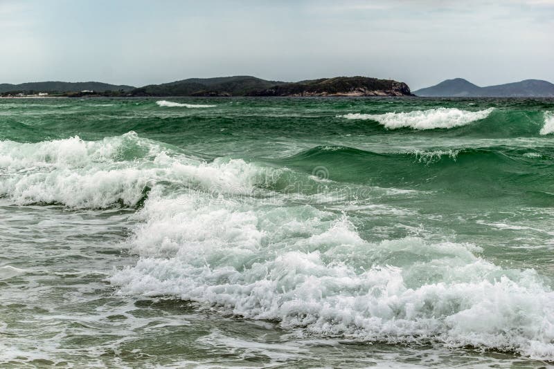 Praia das dunas με κύματα ωκεανού που καλύπτουν τον γαλάζιο ουρανό της παραλίας και τα βουνά στο φόντο. στοκ φωτογραφία με δικαίωμα ελεύθερης χρήσης