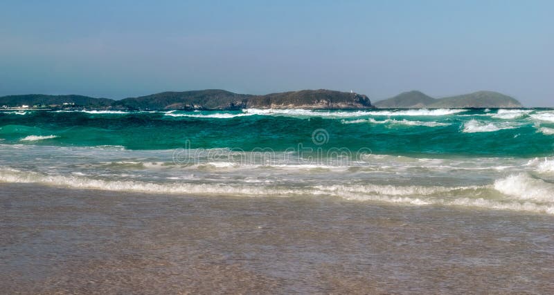 Praia das dunas με κύματα ωκεανού που καλύπτουν τον γαλάζιο ουρανό της παραλίας και τα βουνά στο φόντο. στοκ εικόνες με δικαίωμα ελεύθερης χρήσης