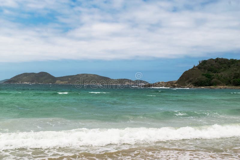 Praia das dunas με κύματα ωκεανού που καλύπτουν τον γαλάζιο ουρανό της παραλίας και τα βουνά στο φόντο. στοκ εικόνα με δικαίωμα ελεύθερης χρήσης