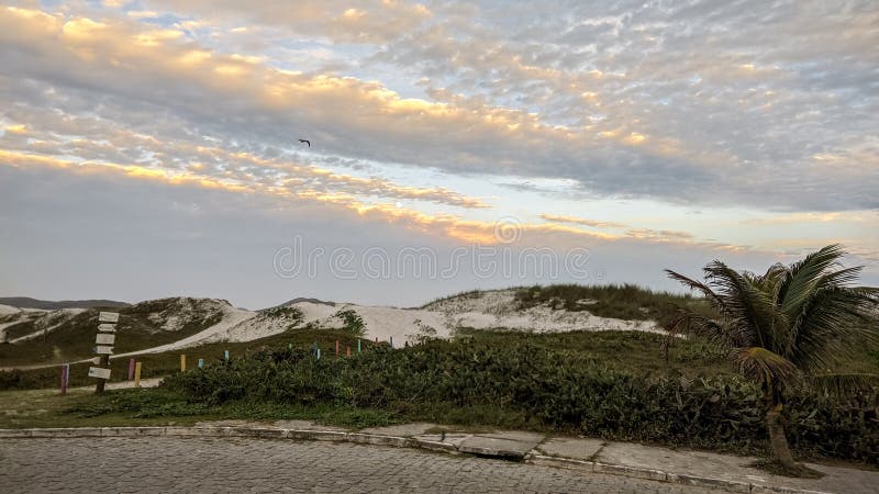 Praia das dunas με μεγάλους αμμώδεις θίνες συννεφιά ουρανός και όμορφο ηλιοβασίλεμα. στοκ εικόνα με δικαίωμα ελεύθερης χρήσης