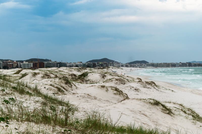 Praia das dunas με μια όμορφη θαλάσσια λευκή αμμώδη θόλο και την πόλη στο παρασκήνιο. στοκ εικόνα με δικαίωμα ελεύθερης χρήσης