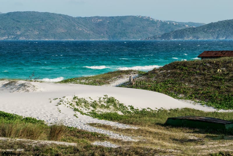 Praia das dunas με υπανάπτυξη από τον γαλάζιο ουρανό και τα βουνά στο φόντο. στοκ εικόνες