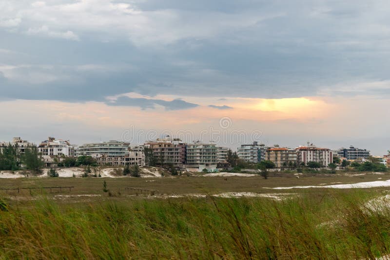 Praia das dunas παραβλέποντας την πόλη λευκοί αμμόλοφοι και όμορφα ηλιοβασίλεμα. όψη praia das dunas με υποανάπτυξη παράκτια κτίρια συννεφιά ουρανός και όμορφο ηλιοβασίλεμα.