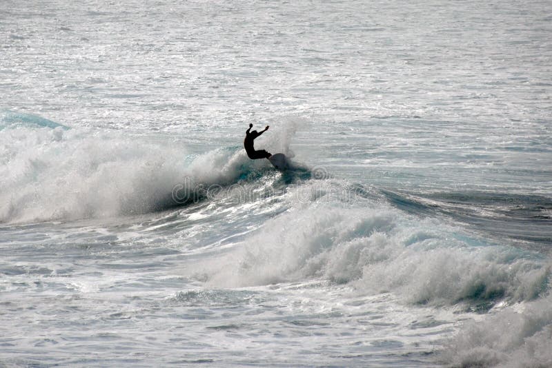 PRAIA DE WAIMEA, ESTADOS UNIDOS DE OAHU, HAVAÍ - 30 DE JANEIRO DE 2015: Silhueta de um surfista que monta uma onda fotografia de stock PRAIA DE WAIMEA, ESTADOS UNIDOS DE OAHU, HAVAÍ - 30 DE JANEIRO DE 2015: Silhueta de um surfista que monta uma onda fotografia de stock
