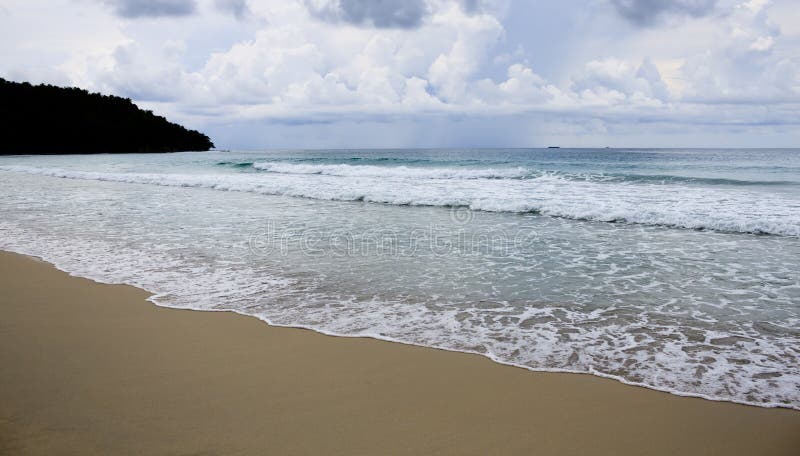 Praia e ondas com céu sombrio imagem de stock