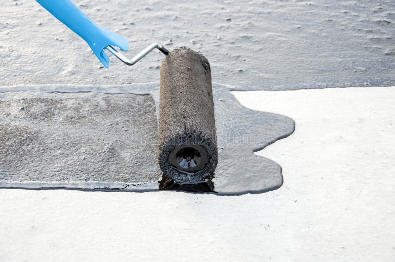 Praimer del betún de la pintura del trabajador del Roofer en la superficie concreta por t foto de archivo libre de regalías Praimer del betún de la pintura del trabajador del Roofer en la superficie concreta por t foto de archivo libre de regalías