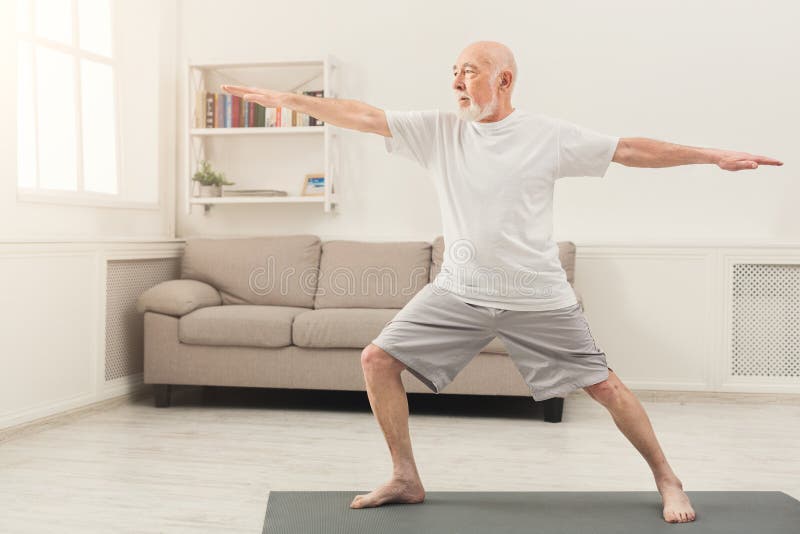 Sporty elderly guy practicing yoga indoors. Senior man doing stretching exercise at home. Active lifestyle and healthcare in any age, copy space. Sporty elderly guy practicing yoga indoors. Senior man doing stretching exercise at home. Active lifestyle and healthcare in any age, copy space