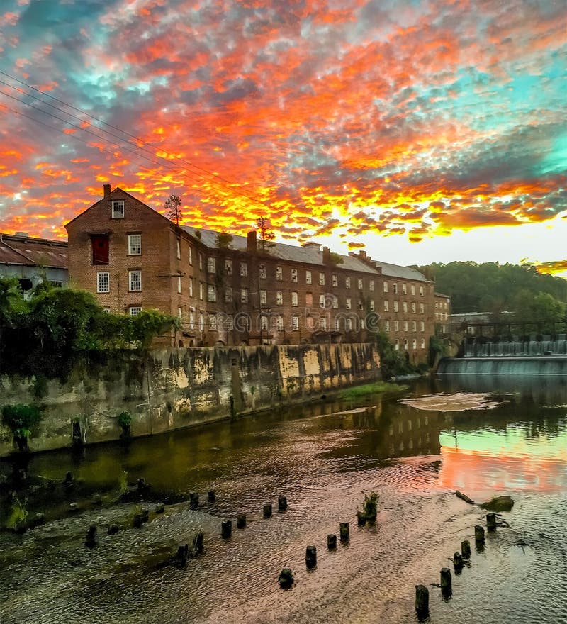 Prattville, Alabama, USA - October 6, 2016: Prattville Gin Company and Autauga Creek with a dramatic sunset and cloudscape. Prattville, Alabama, USA - October 6, 2016: Prattville Gin Company and Autauga Creek with a dramatic sunset and cloudscape.