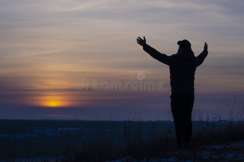 Worship. Silhouette of a man with arms stretched out to the sky