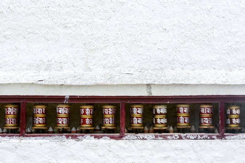 Prayer wheels on white wall