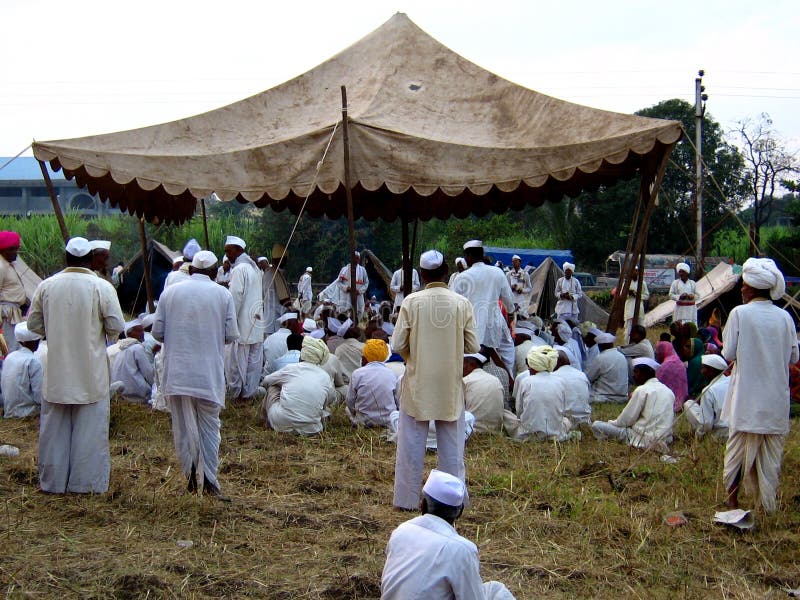 Pilgrims gather in thousands at the pilgrimmage of Alandi near the city of Pune in India. The people live in tents and gather in groups under the tent of their leader and sing BHAJANS (Devotional songs) together. They dance with it sometimes. Seen in this picture is a get-together of one of the group of the pilgrims before their dinner singing BHAJANS The pilgrims walk hundreds of miles barefooted to visit the place on this auspicious day. Pilgrims gather in thousands at the pilgrimmage of Alandi near the city of Pune in India. The people live in tents and gather in groups under the tent of their leader and sing BHAJANS (Devotional songs) together. They dance with it sometimes. Seen in this picture is a get-together of one of the group of the pilgrims before their dinner singing BHAJANS The pilgrims walk hundreds of miles barefooted to visit the place on this auspicious day.