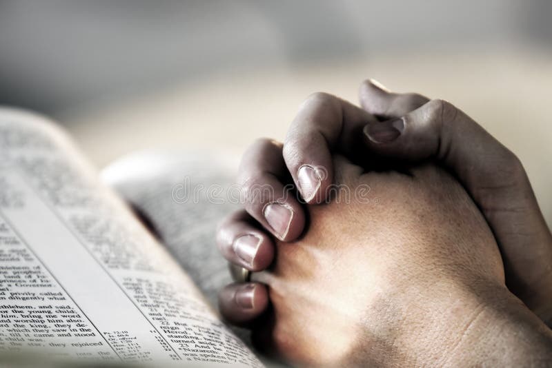 A mans Hände faltete im Gebet über die Heilige Bibel darstellen, glauben und Spiritualität im Alltag.