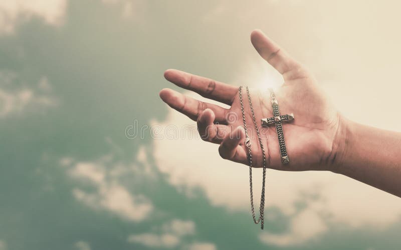 Praying hands hold a crucifix or cross of metal necklace with faith in religion and belief in God on confession background. Power