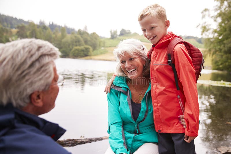 Pre-teen boy standing beside his grandparents, sitting on the shore of a lake, Lake District, UK stock image Pre-teen boy standing beside his grandparents, sitting on the shore of a lake, Lake District, UK stock image